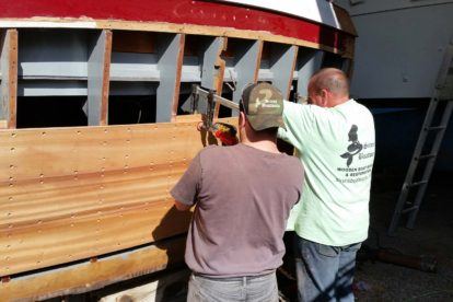 two people working on a Chris Craft cruiser boat