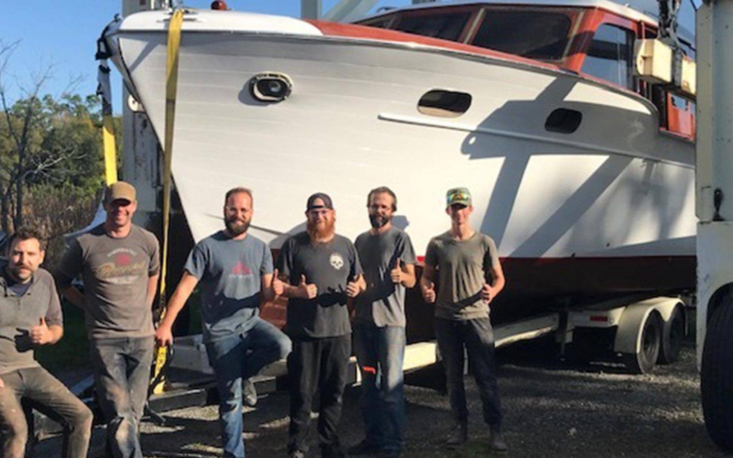 six sirens boatworks employees standing in front of a large boat