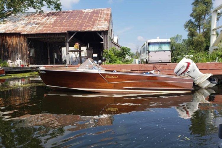 wooden boat with a large motor docked in the water