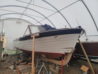 wooden boat being worked on in a tent